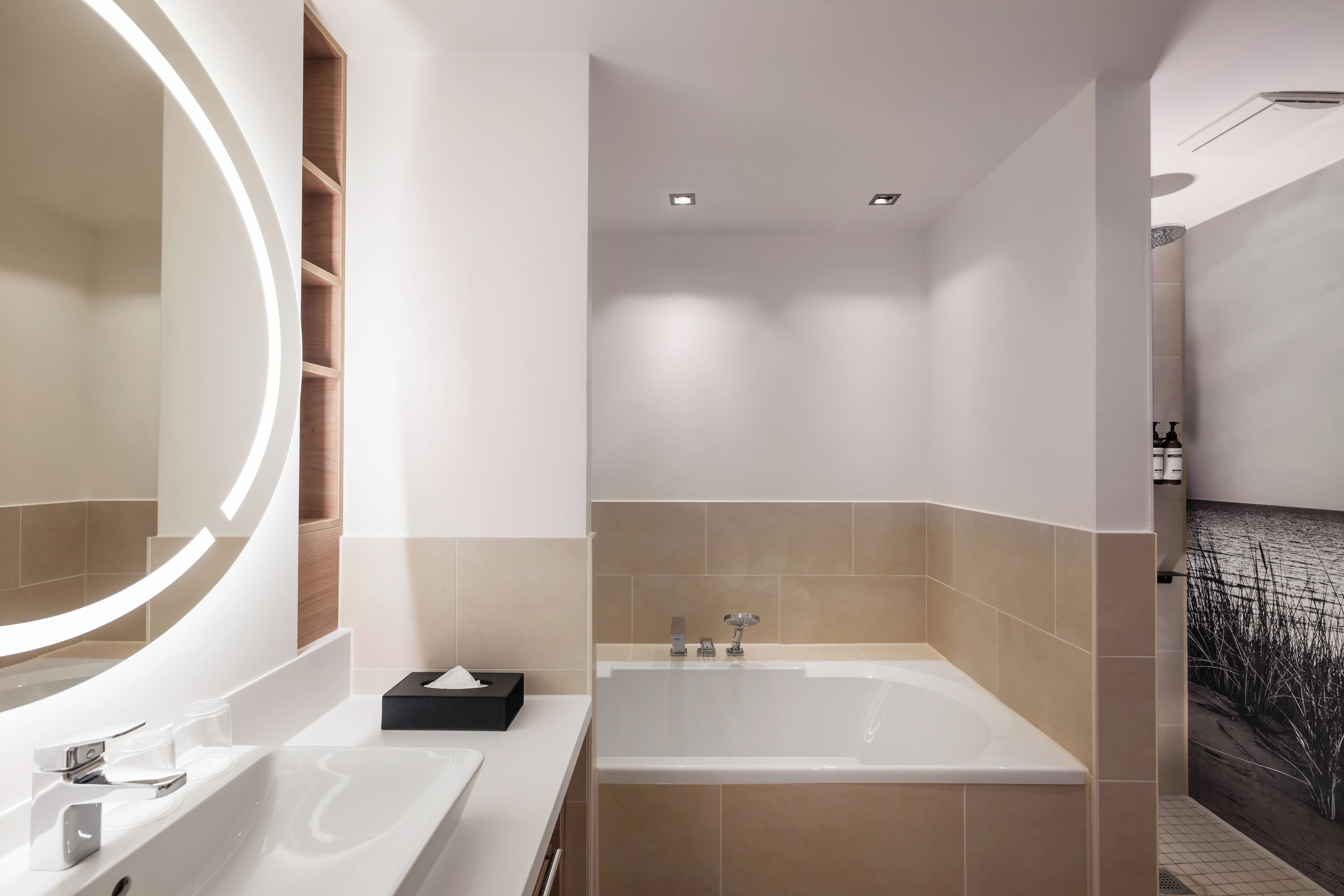 A modern bathroom with a large mirror, a bathtub, and a vanity with a sink.