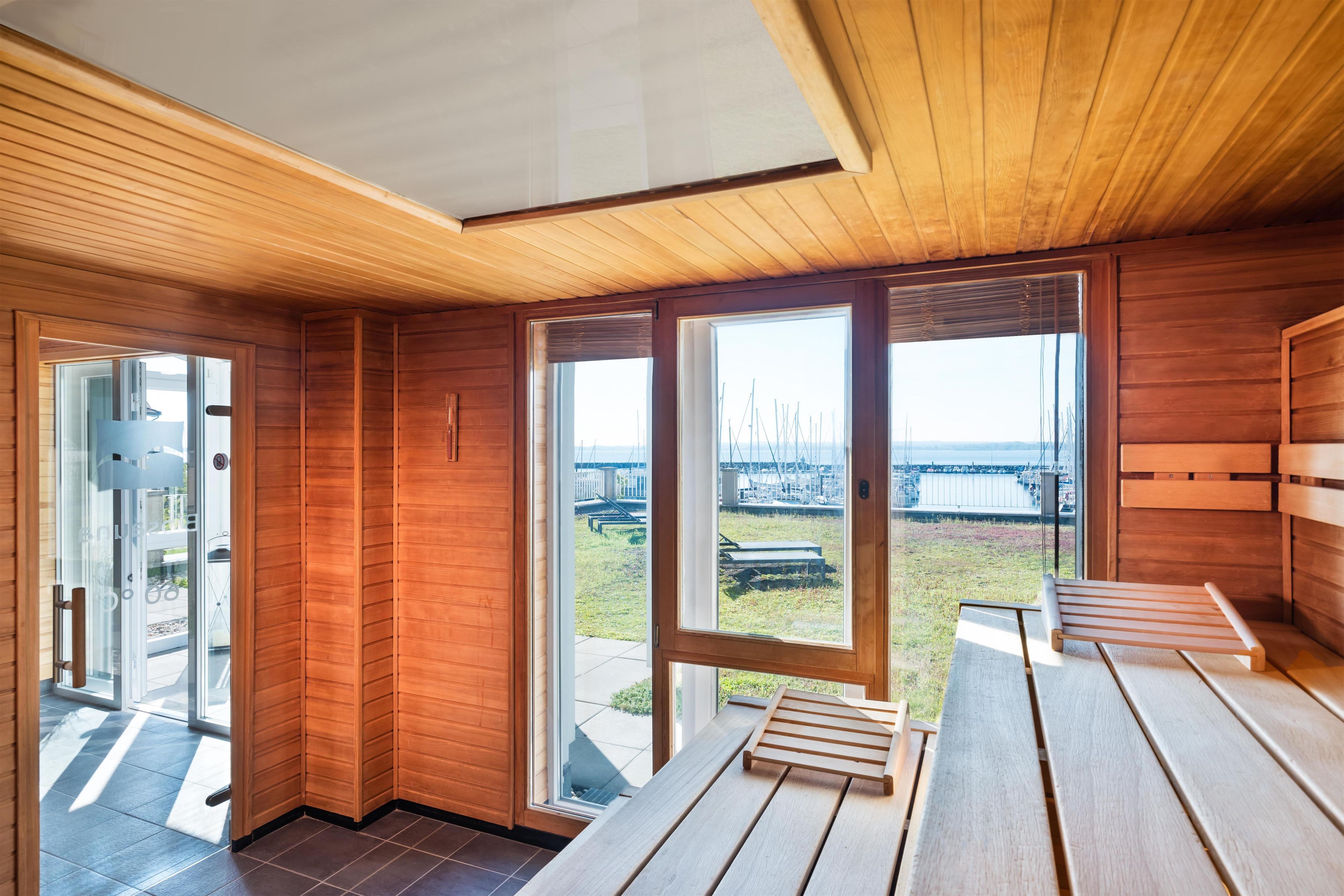 A modern interior with wooden paneling, large windows, and a view of a marina.