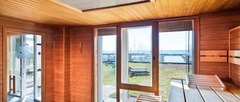 Un intérieur moderne avec des lambris en bois, de grandes fenêtres et une vue sur un port de plaisance.