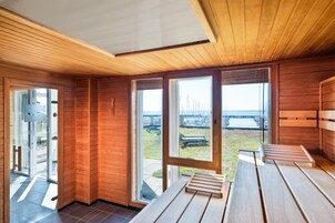Un interior moderno con paneles de madera, ventanas amplias y vistas a un puerto deportivo.