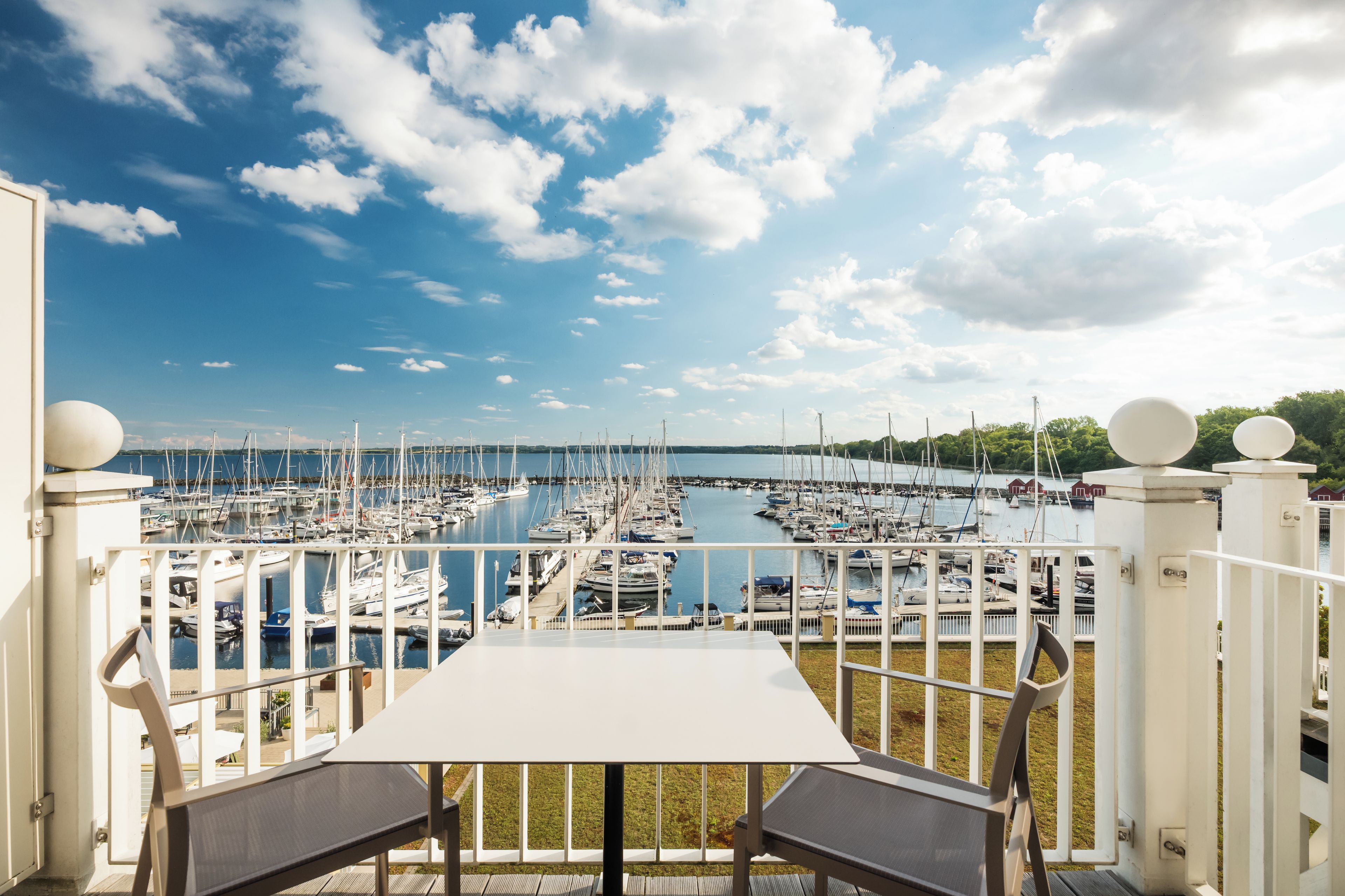 A terrace with a table and chairs overlooking a marina with numerous boats.