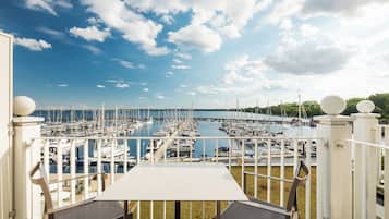 A terrace with a table and chairs overlooking a marina with numerous boats.
