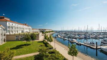 Un puerto deportivo con barcos amarrados, un edificio con tejado rojo y un área verde con árboles.