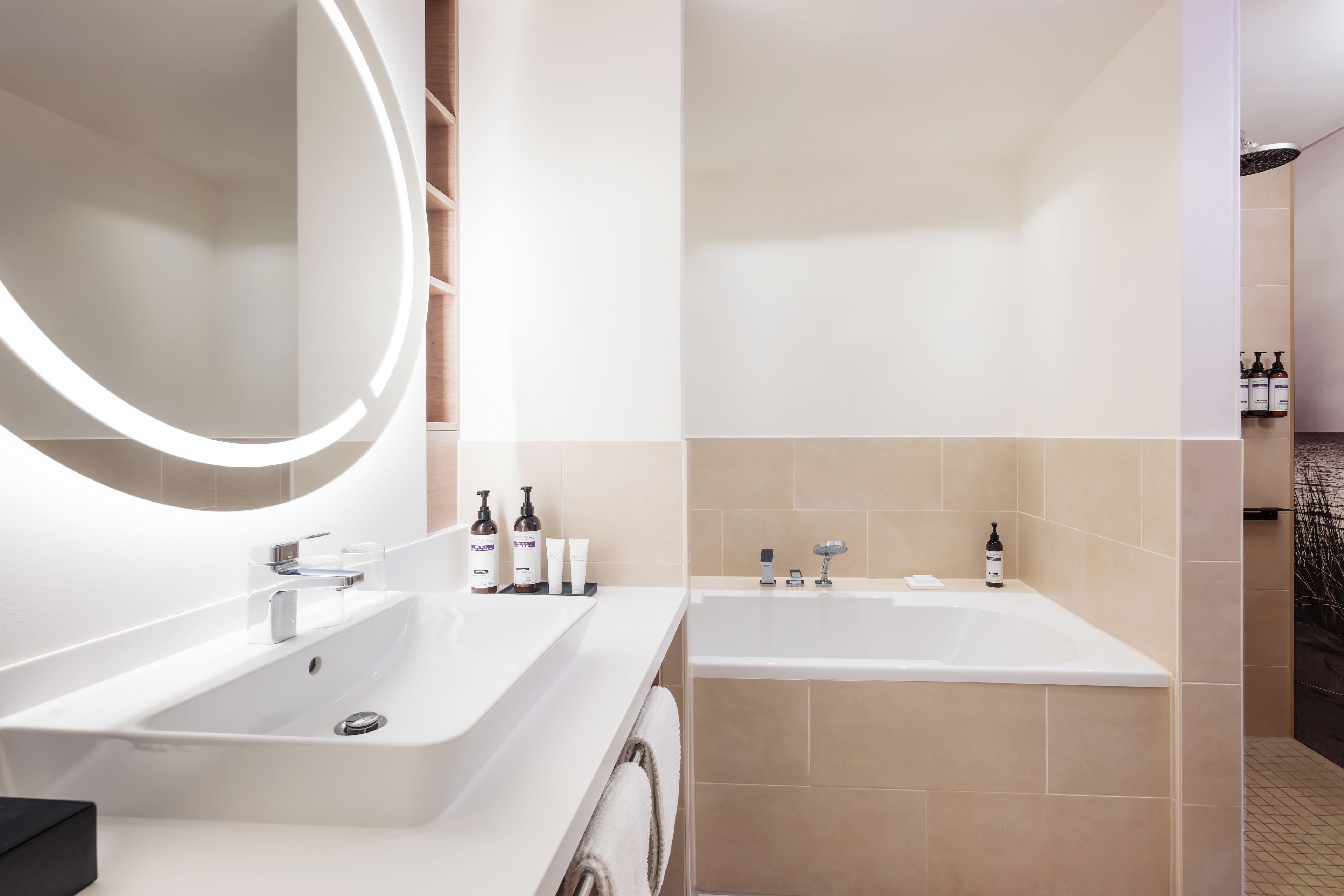 A modern bathroom with two sinks, a large mirror, and a bathtub.