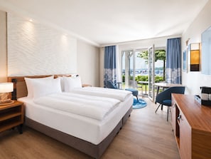 A hotel room with a bed, a desk, a chair, and a view of the outdoors. - MAREBALTIC (Boltenhagen)