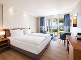 Hotellihuone, jossa on sänky, työpöytä, tuoli ja näkymä ulos.