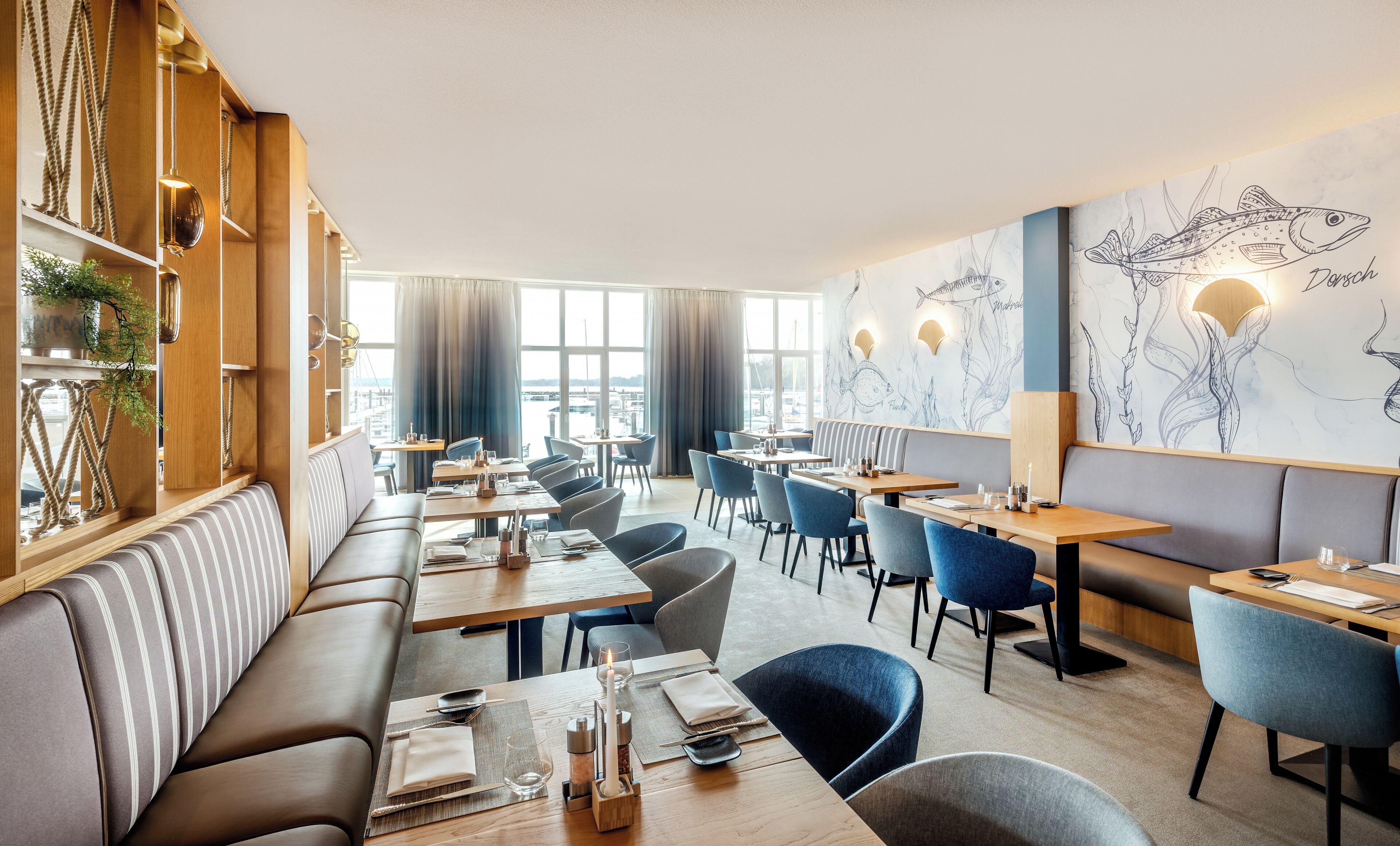 A modern restaurant with a long counter, blue chairs, and a mural of fish on the wall.