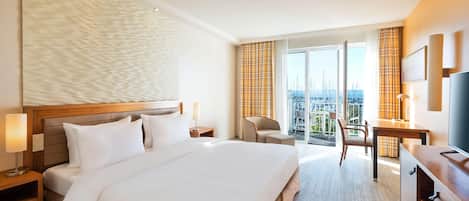 Ein Hotelzimmer mit einem großen Bett, einem Schreibtisch, einem Sessel und einem Fernseher.