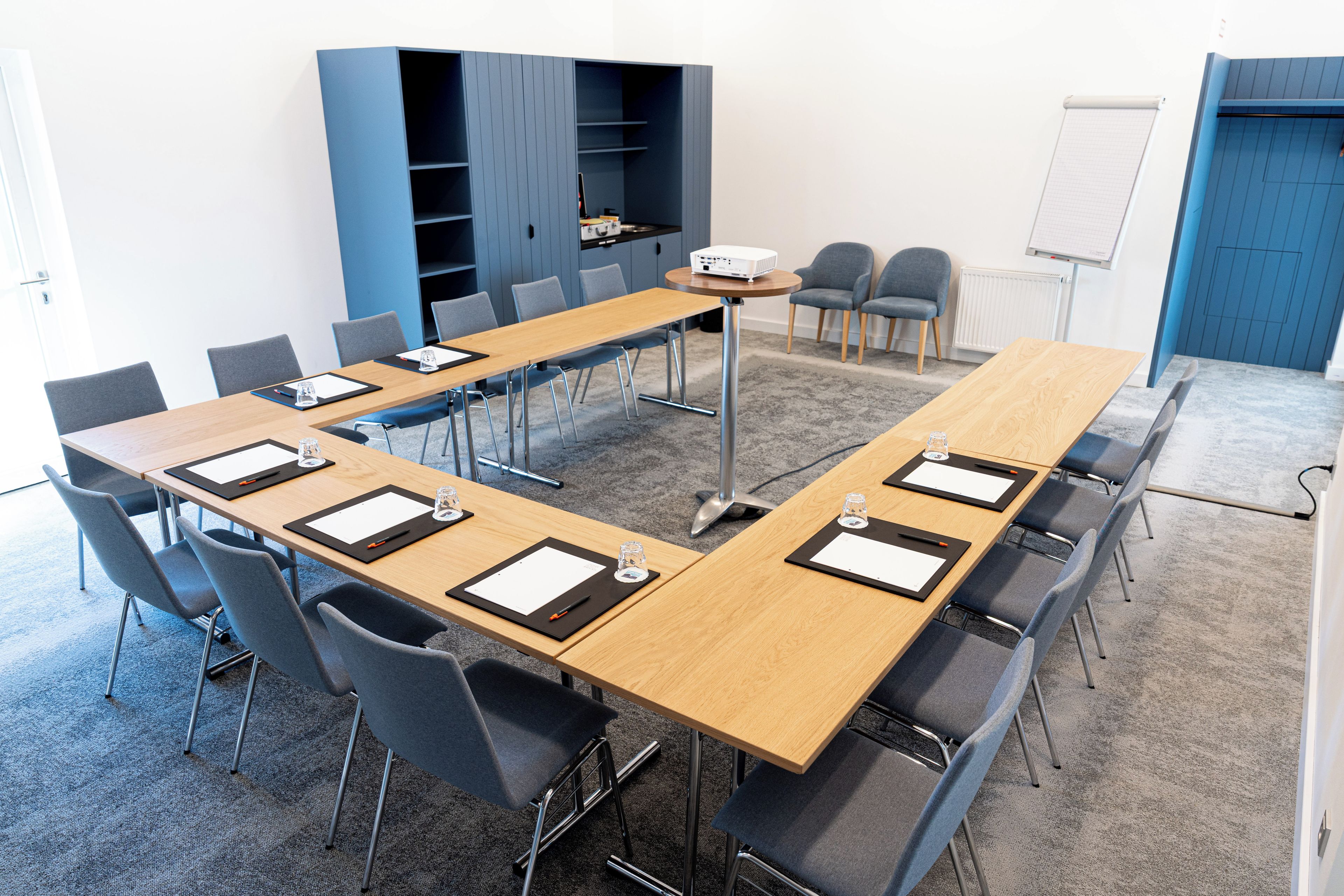 A conference room with a long table, multiple chairs, a projector, and a whiteboard.
