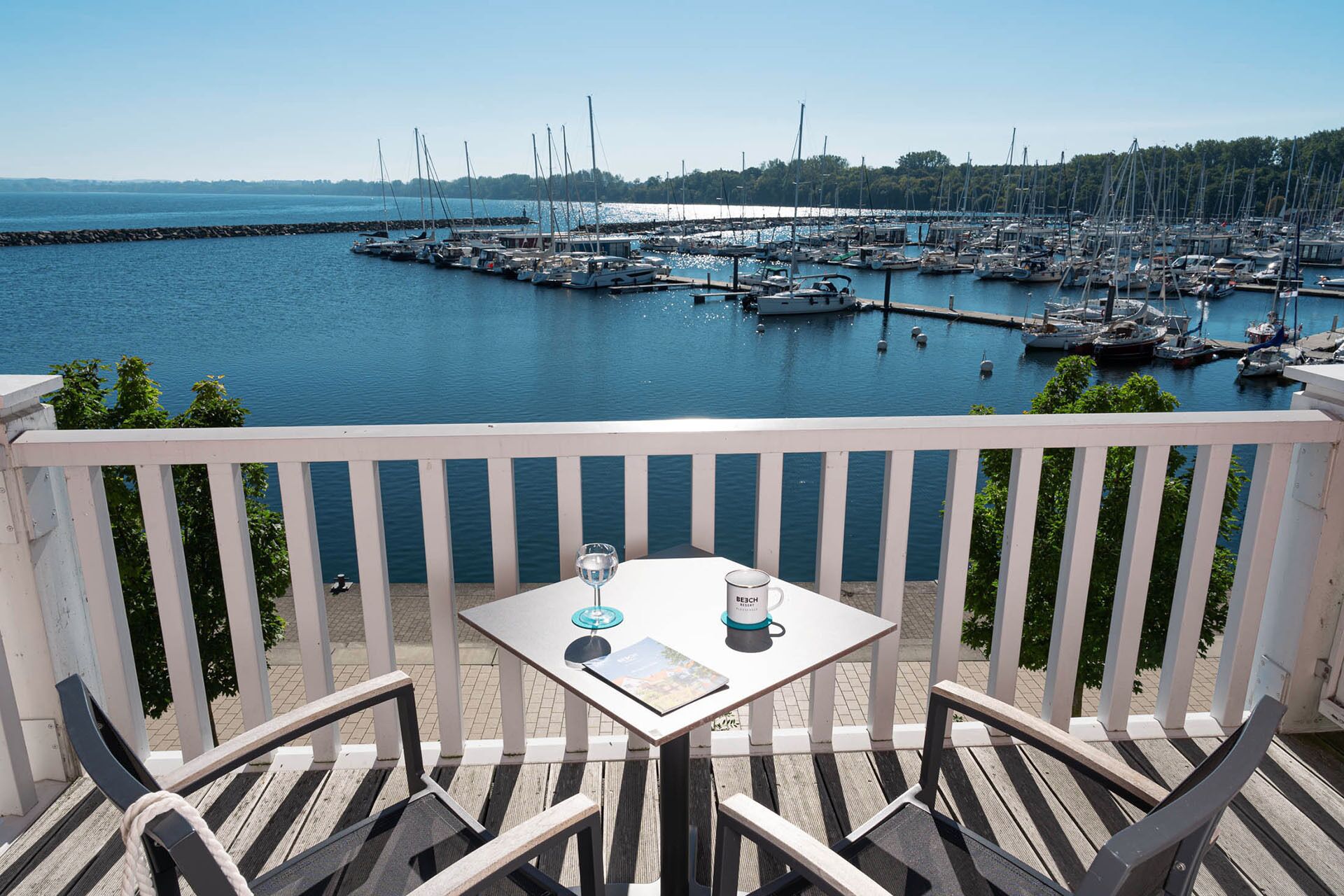 Ein Balkon mit Tisch und Stühlen mit Blick auf einen Yachthafen und Boote.