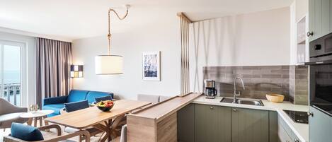 A compact kitchen with a dining area, a coffee machine, and a view of the sea through the window.