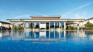 A modern hotel with a large swimming pool, a covered outdoor area, and a clear view of the surrounding neighborhood.