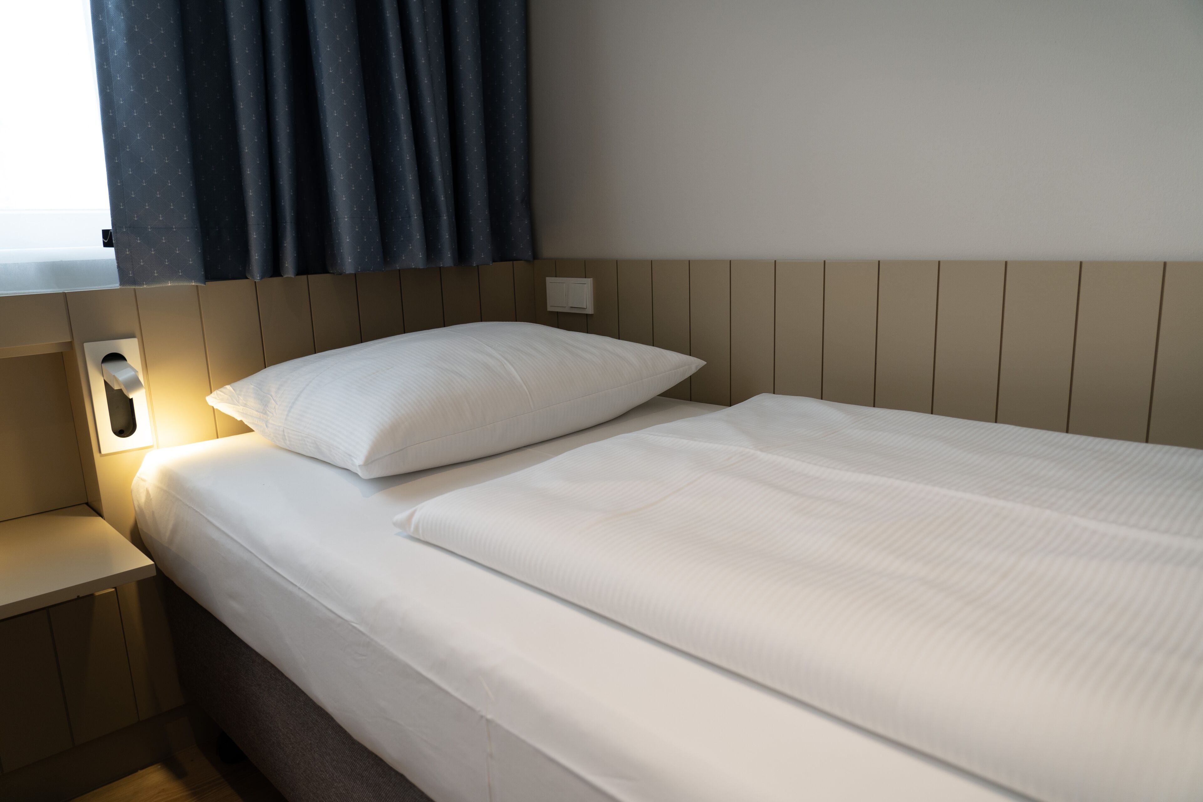 Una cama bien hecha con sábanas blancas en una habitación de hotel.