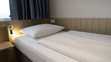 A neatly made bed with white linens in a hotel room.