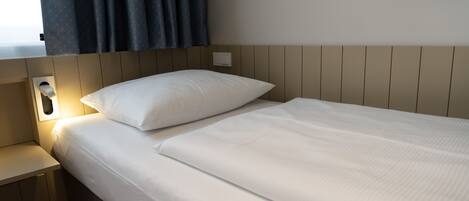 Una cama bien hecha con sábanas blancas en una habitación de hotel.