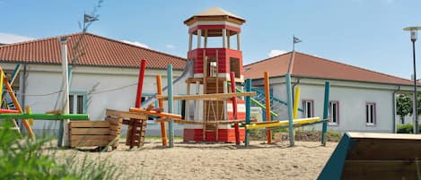 Un parque infantil con un tobogán, estructuras para escalar y una torre de vigilancia.