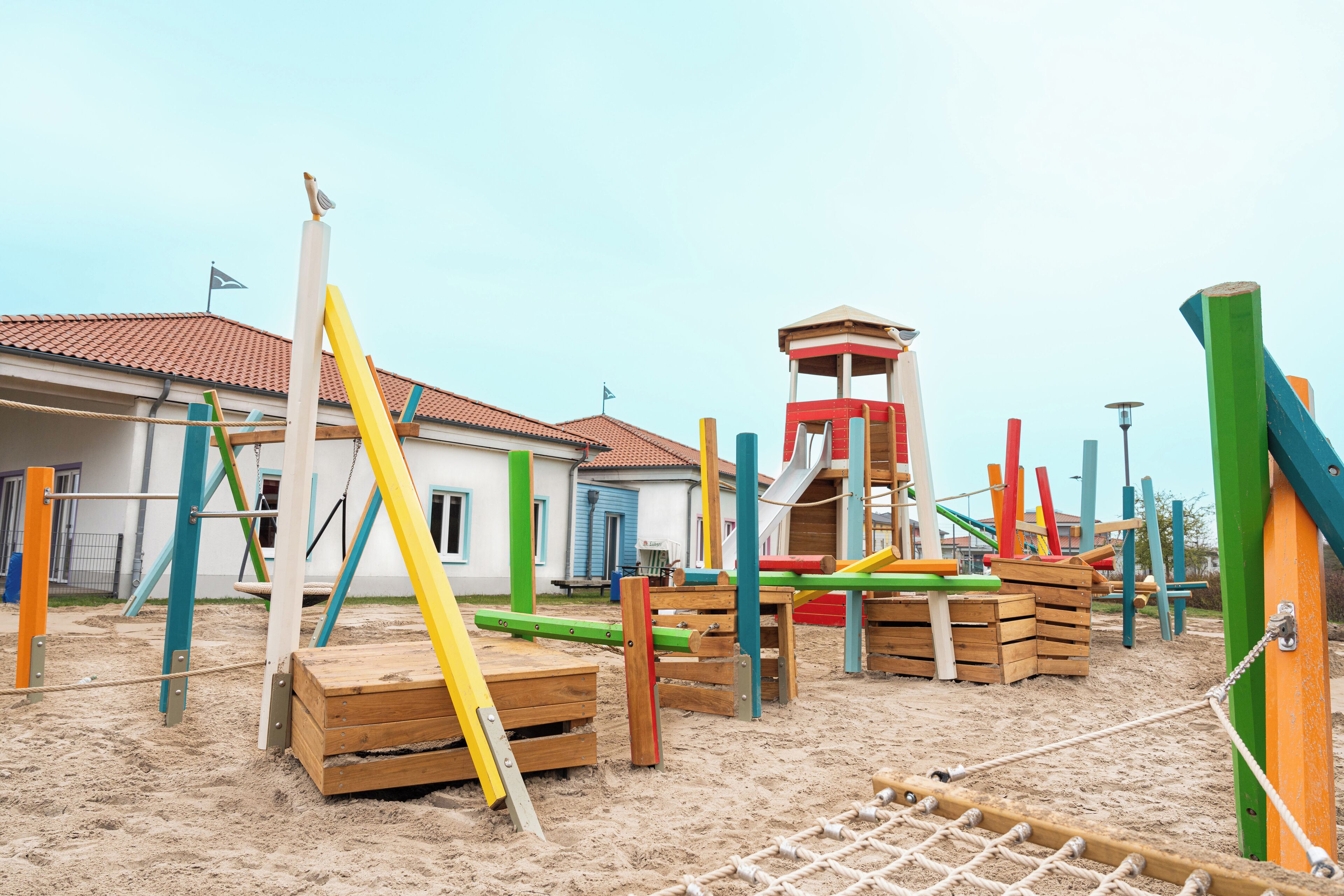 Ein Spielplatz mit verschiedenen Spielgeräten und einem kleinen Gebäude im Hintergrund.