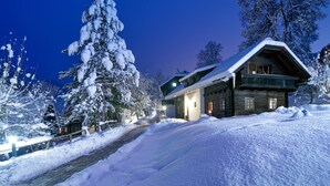 Een besneeuwde lodge met een houten gevel, een schuin dak en een duidelijke ingang.