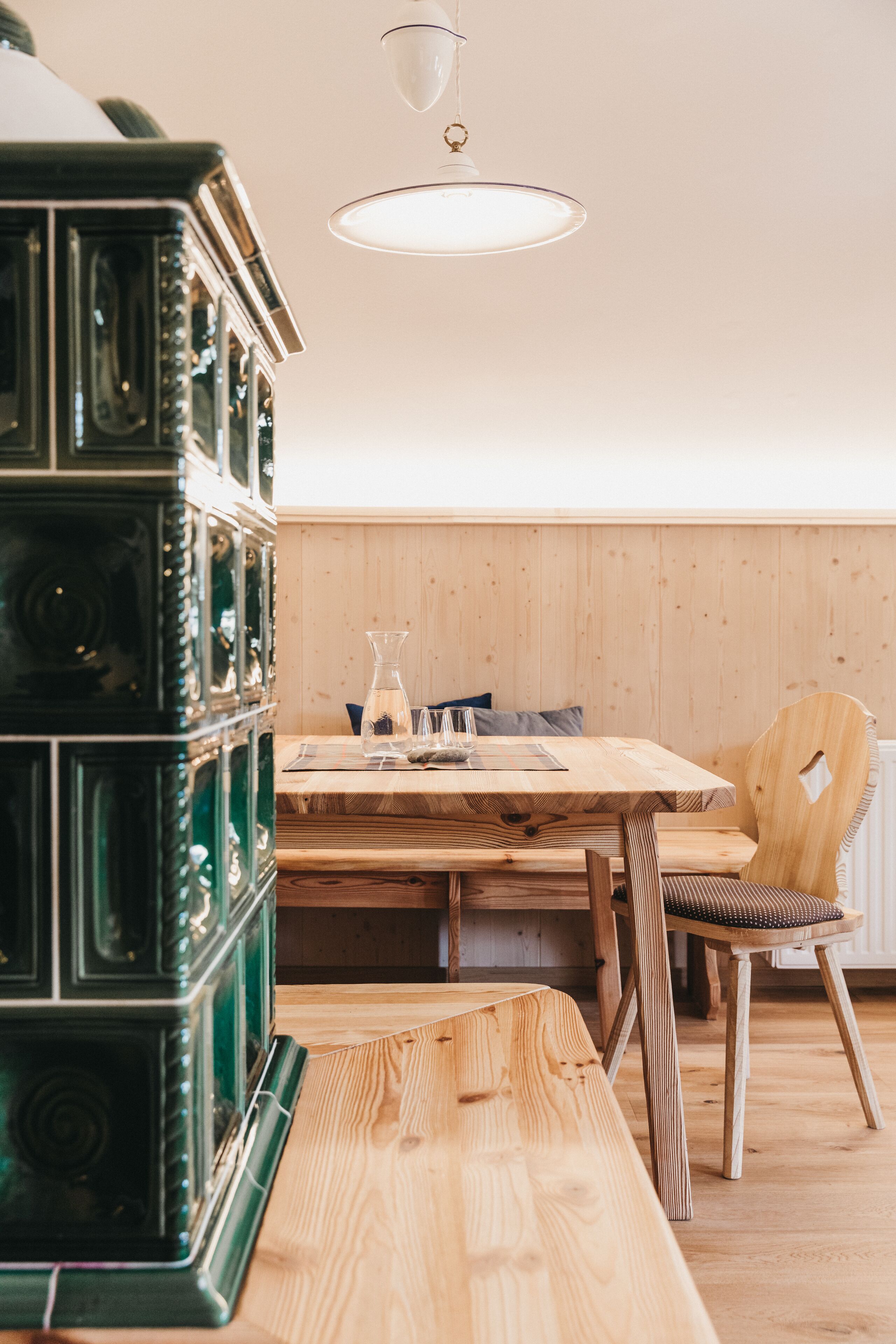 Une table à manger en bois avec des chaises, un meuble vert et un luminaire suspendu dans une pièce aux murs en bois.