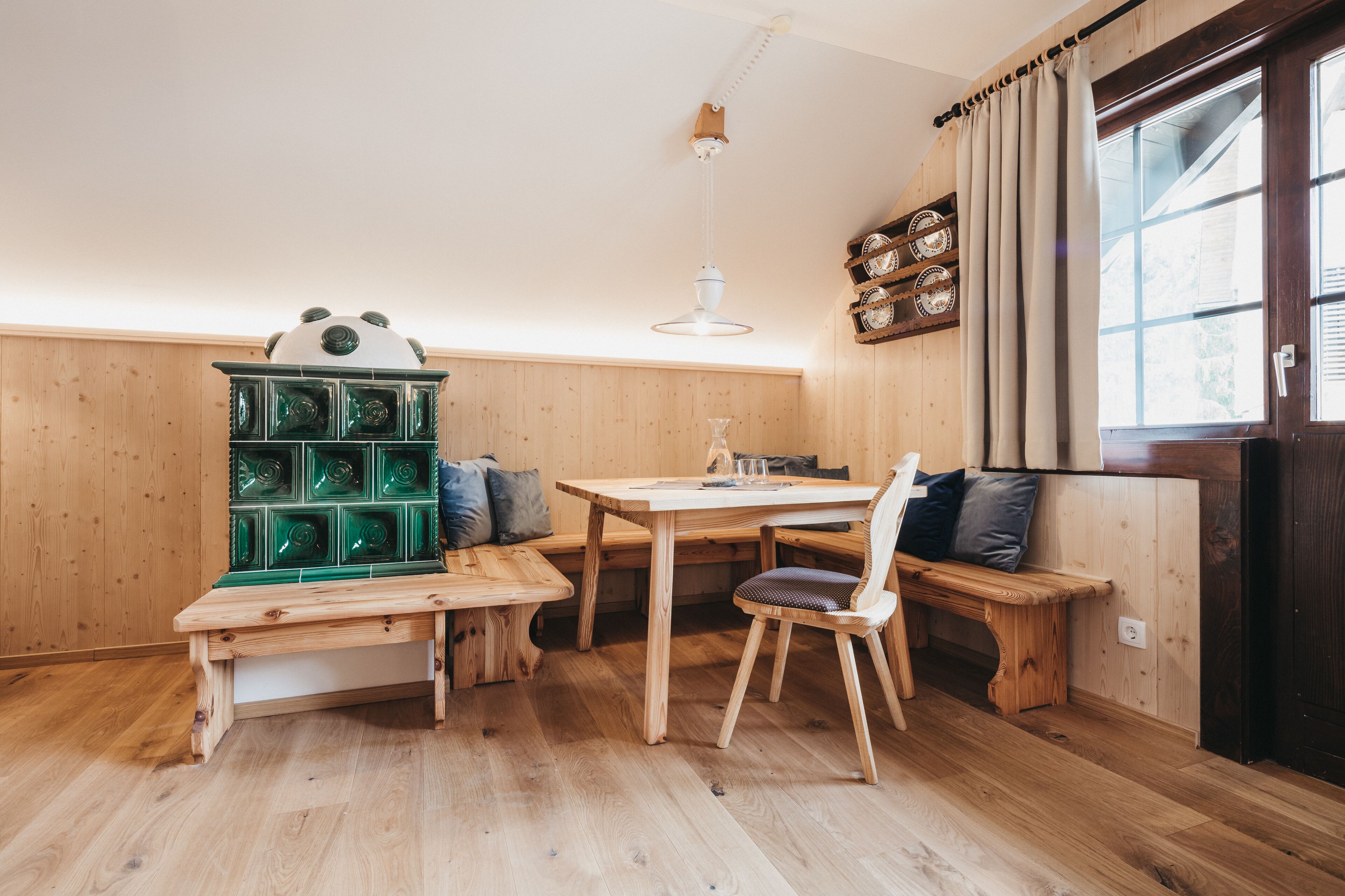 A wooden interior with a wooden bench, a table, and a green cabinet.