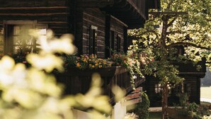 Een houten chalet met een balkon versierd met bloemen, omringd door groen.
