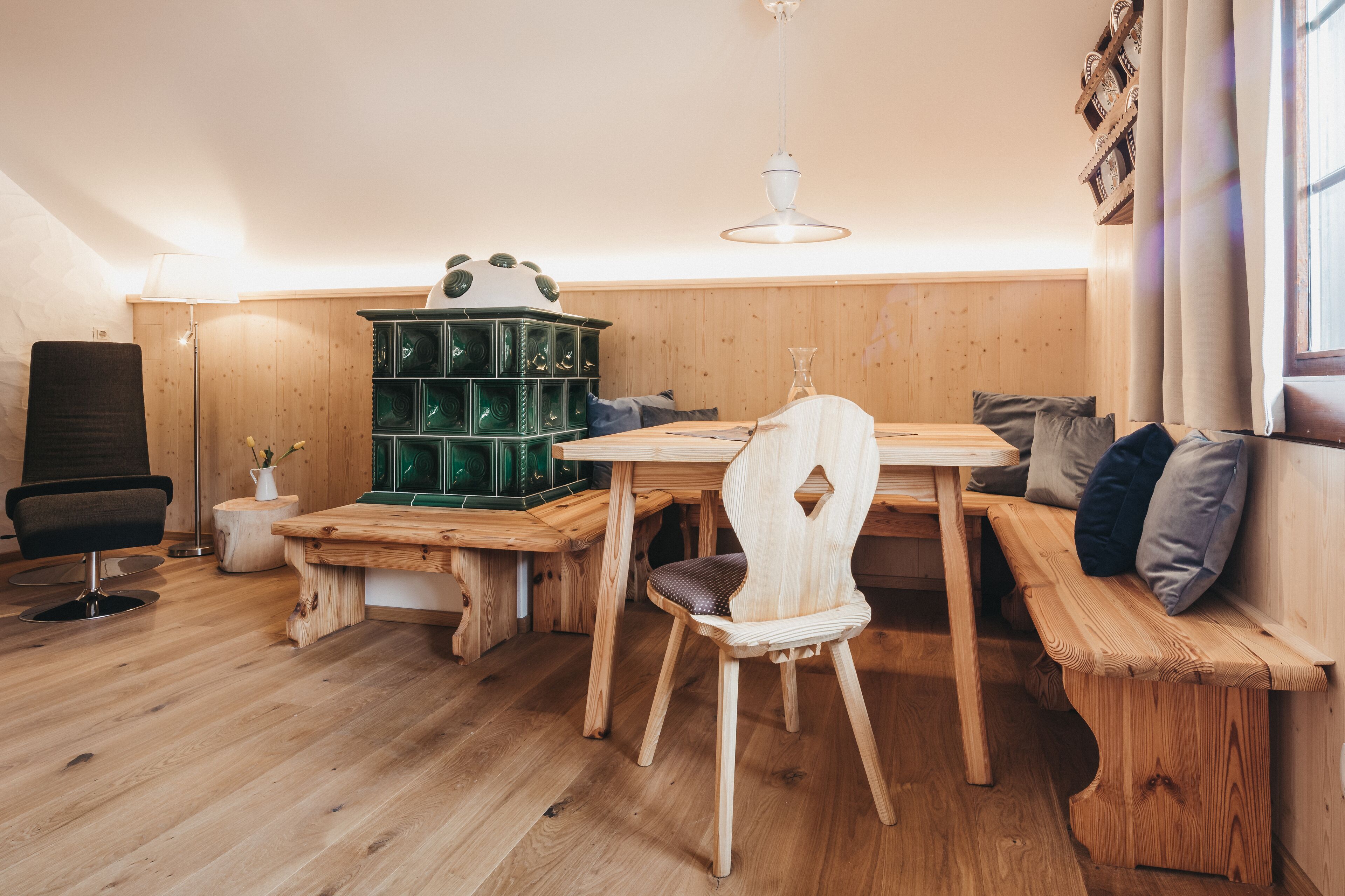 A cozy room with a wooden bench, a dining table, and a green storage unit.