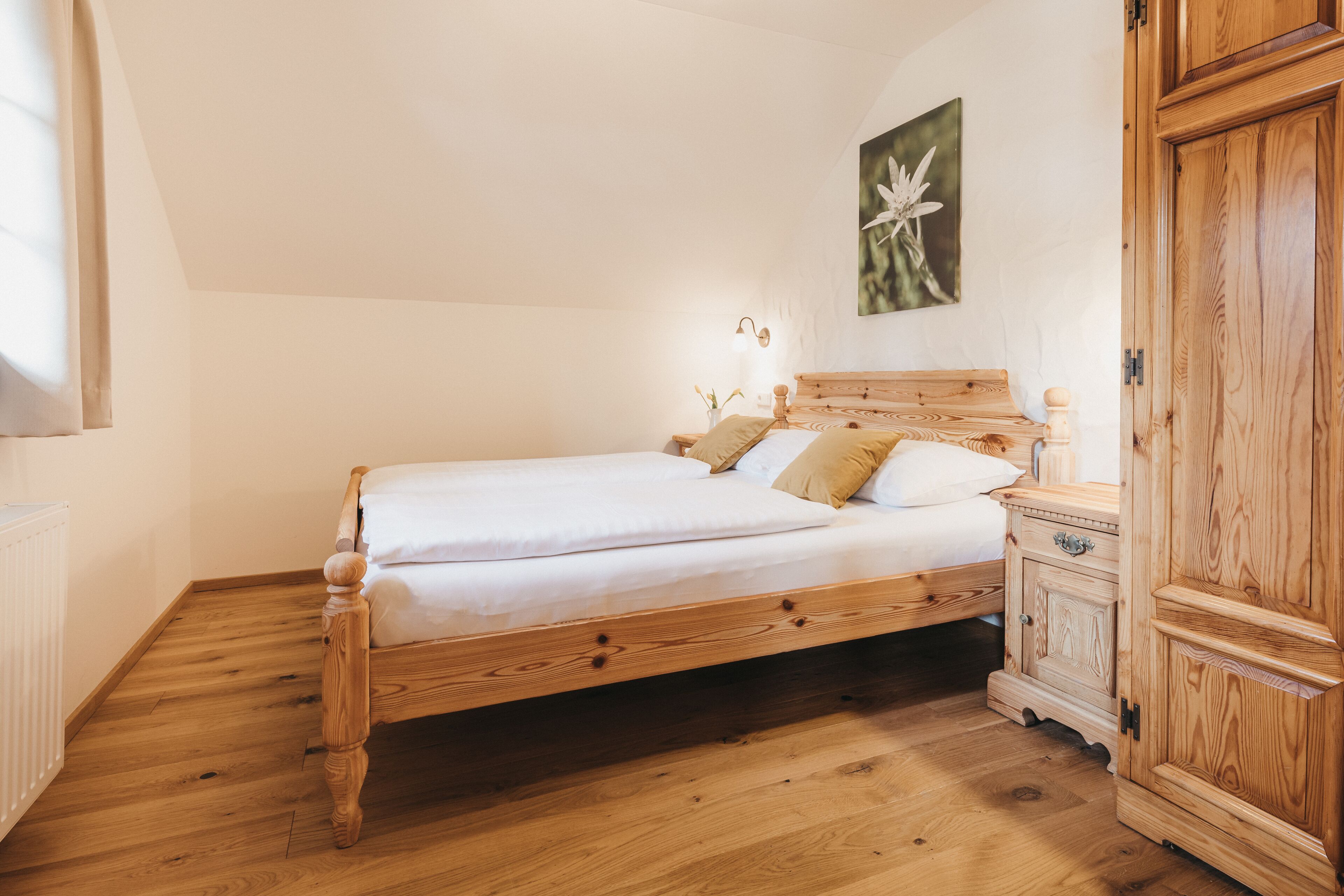 Un lit en bois avec une tête de lit, une table de chevet avec une lampe et une armoire en bois.