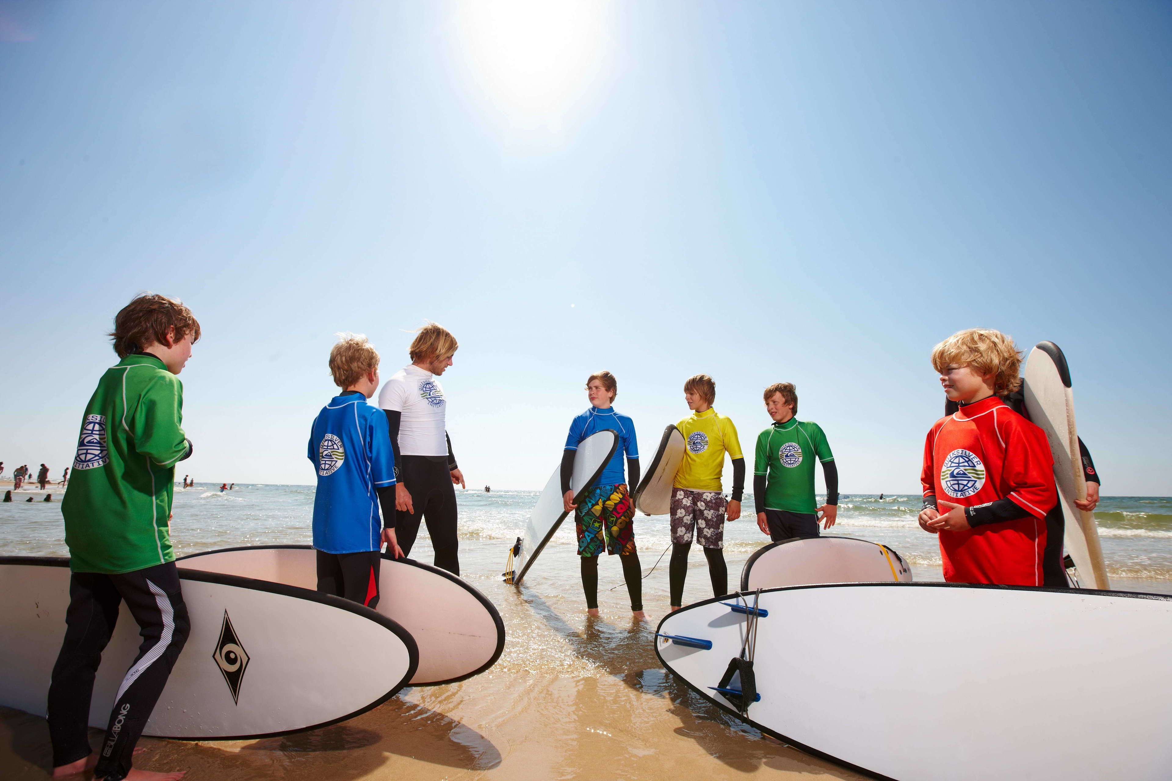 A group of people with surfboards at a beach.