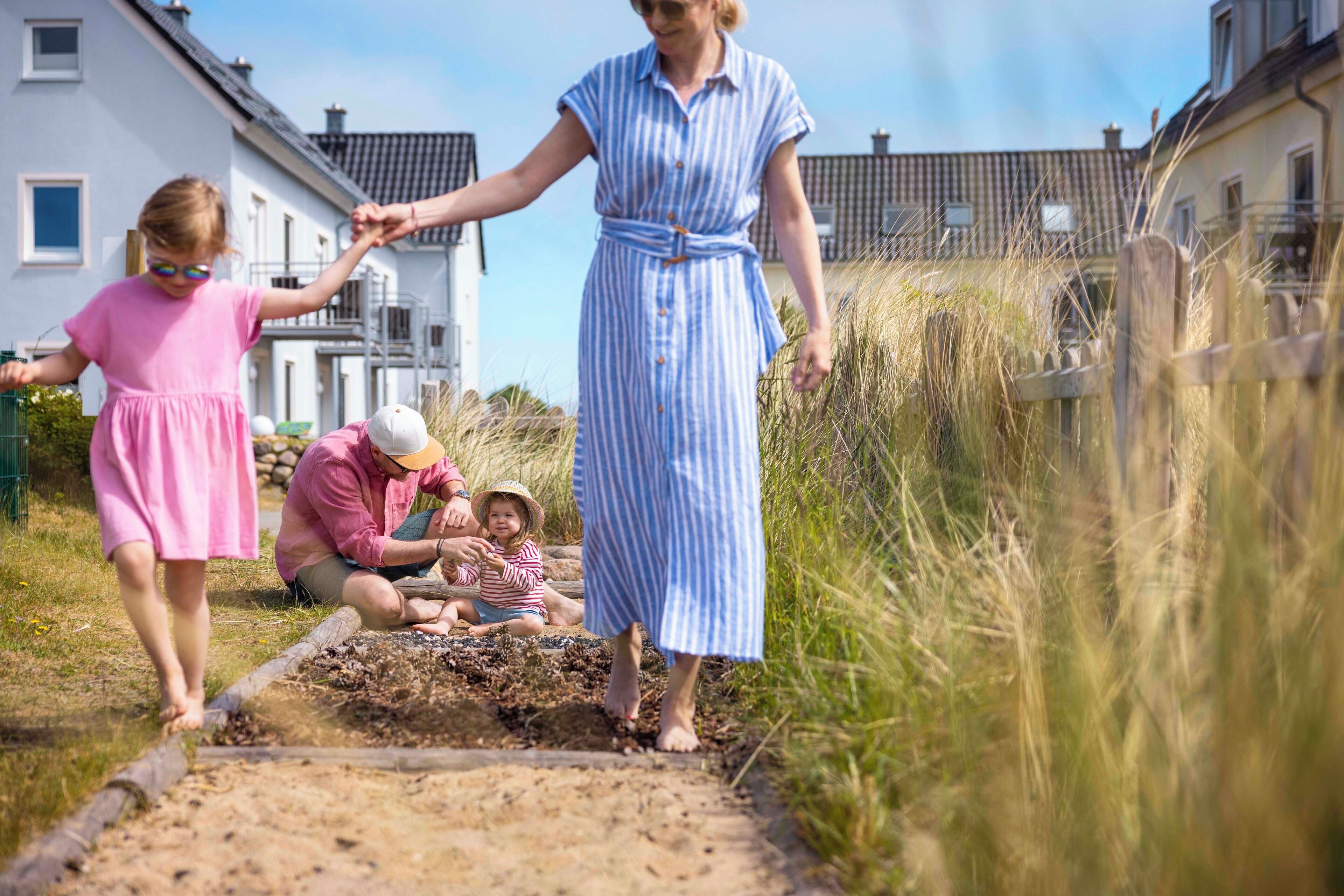 Un chemin bordé de maisons de chaque côté, une zone herbeuse et une personne qui marche.