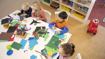A classroom with children engaged in a craft activity, surrounded by various art supplies and educational materials.