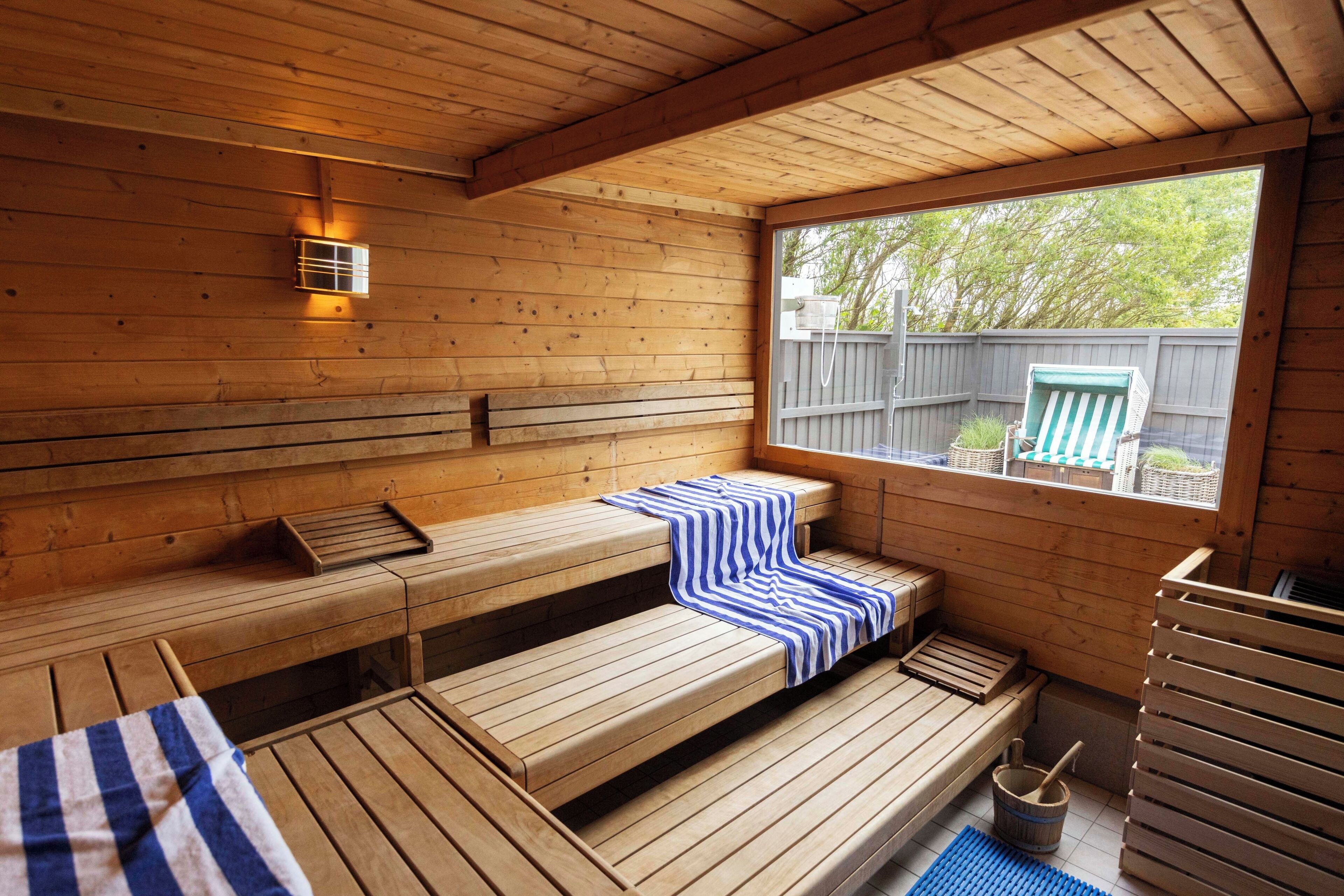 A wooden sauna with benches, a window, and a wooden bench with a towel.