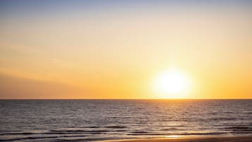 Een strand met de ondergaande zon boven de oceaan.