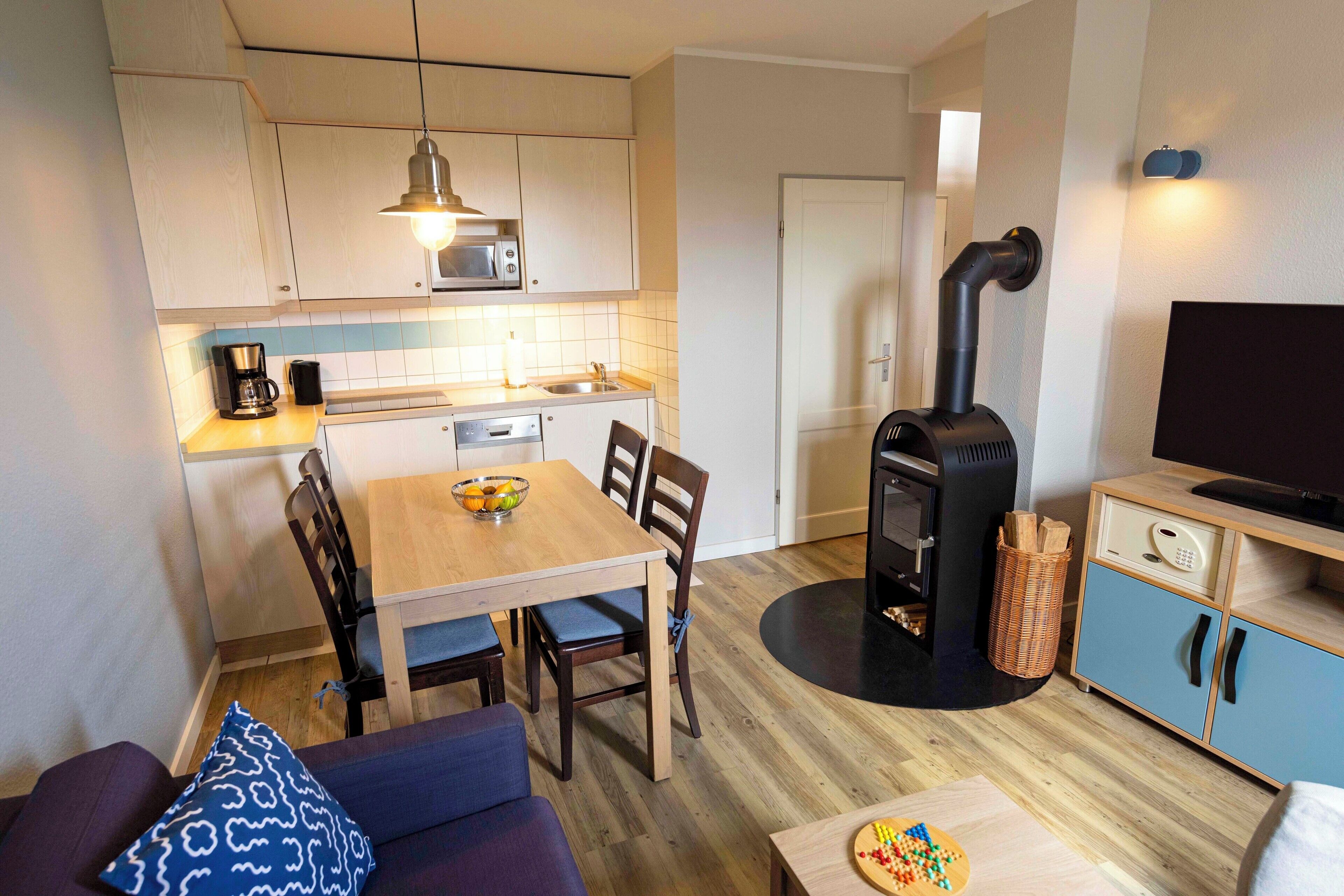 A compact living space with a kitchenette, dining area, and a built-in wood stove.