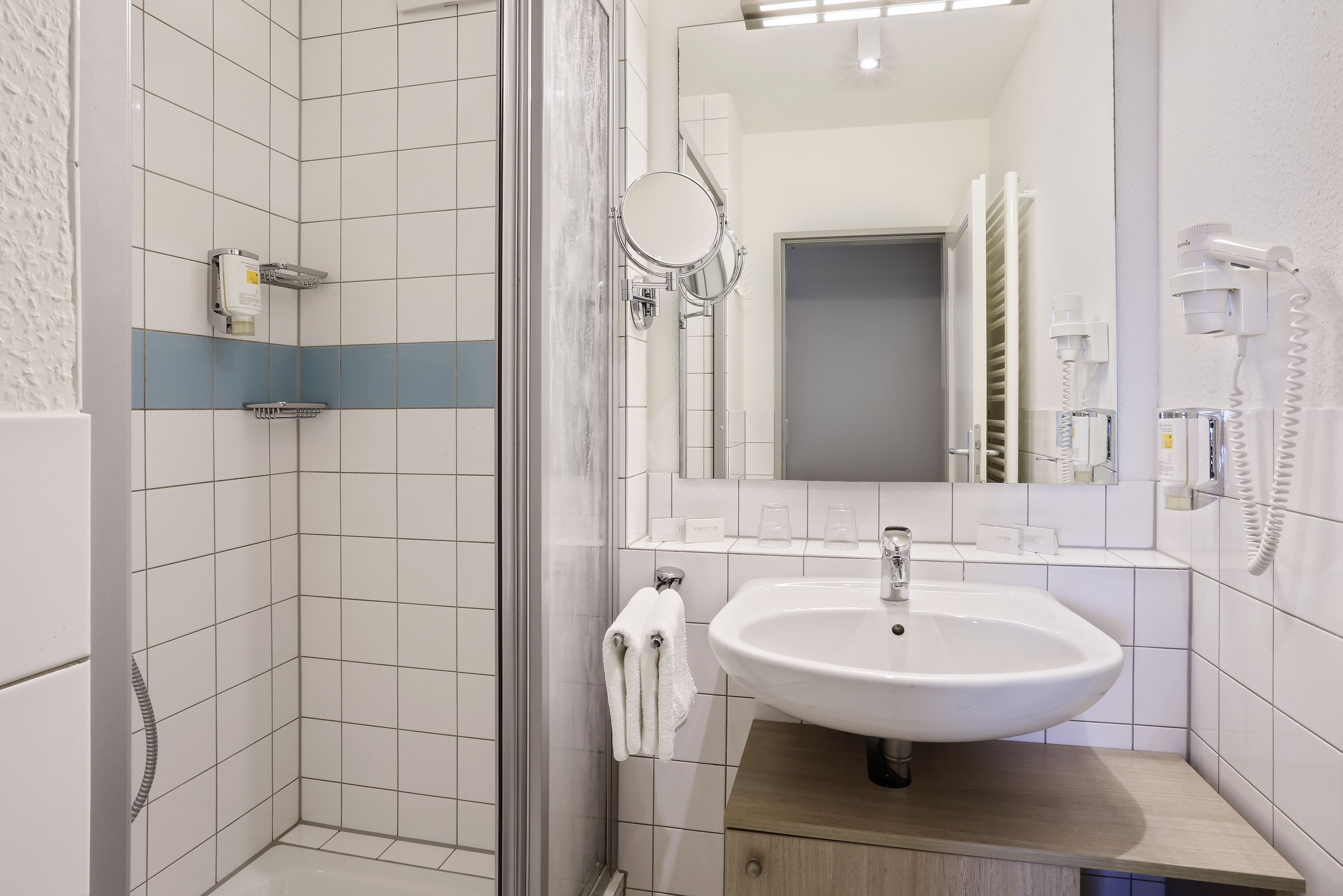 A modern bathroom with a glass-enclosed shower, a white sink, and a mirror above it.