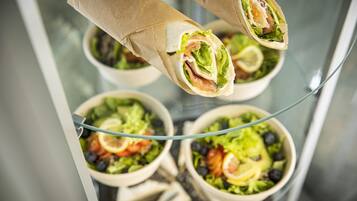 A glass display case with various salads and wraps.