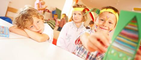 Une salle de classe où des enfants participent à des activités, avec un tableau blanc et du matériel pédagogique.