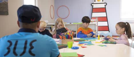A group of children engaged in a craft activity at a table with various colored papers and scissors.