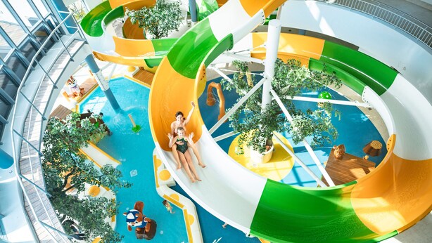 Parque acuático interior de varios niveles con toboganes y piscinas.