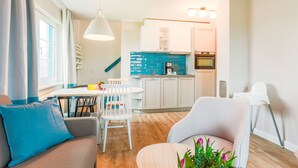 Una sala de estar moderna con un sofá, una mesa de comedor y una zona de cocina con armarios y un fregadero.