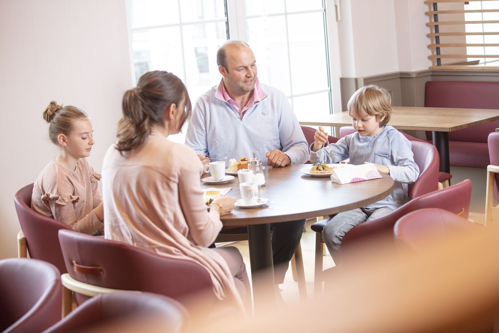 Une famille est assise autour d’une table ronde et mange.