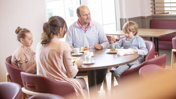 Eine Familie sitzt an einem runden Tisch mit Stühlen darum.
