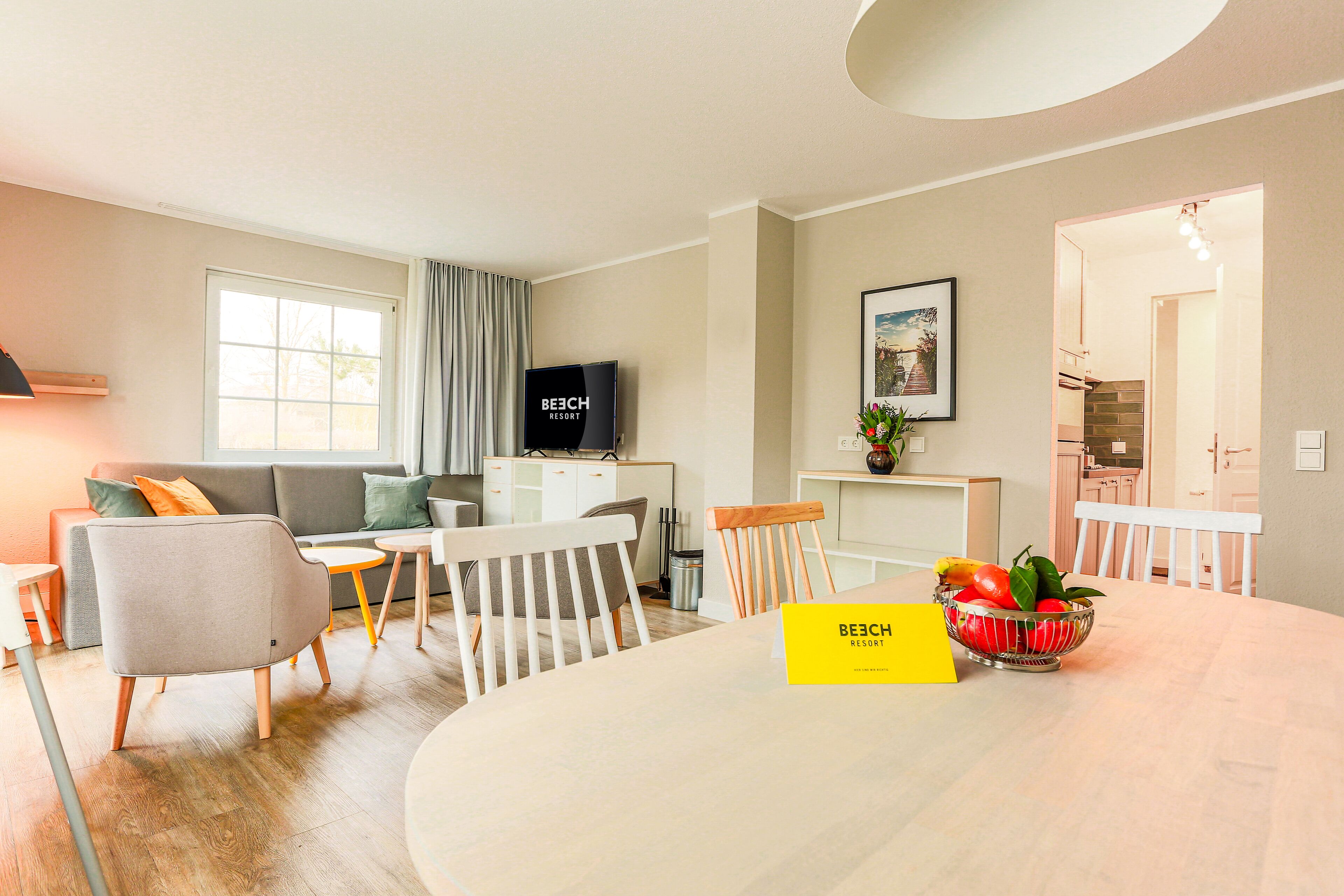 A modern living room with a sofa, chairs, a dining table, and a TV.