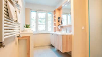 Un baño moderno con ducha integrada, un espejo grande y una ventana que proporciona luz natural.