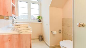 Een moderne badkamer met toilet, wastafel en raam.