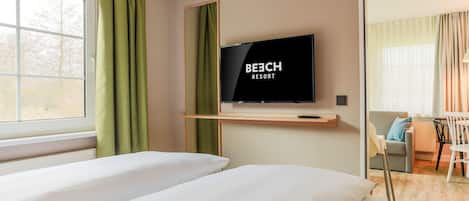 Een hotelkamer met een bed, een aan de muur bevestigde televisie, een bureau en een stoel.