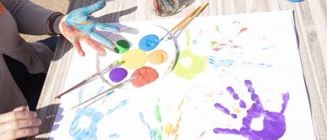 A person painting on a large paper with various colors of paint and brushes.