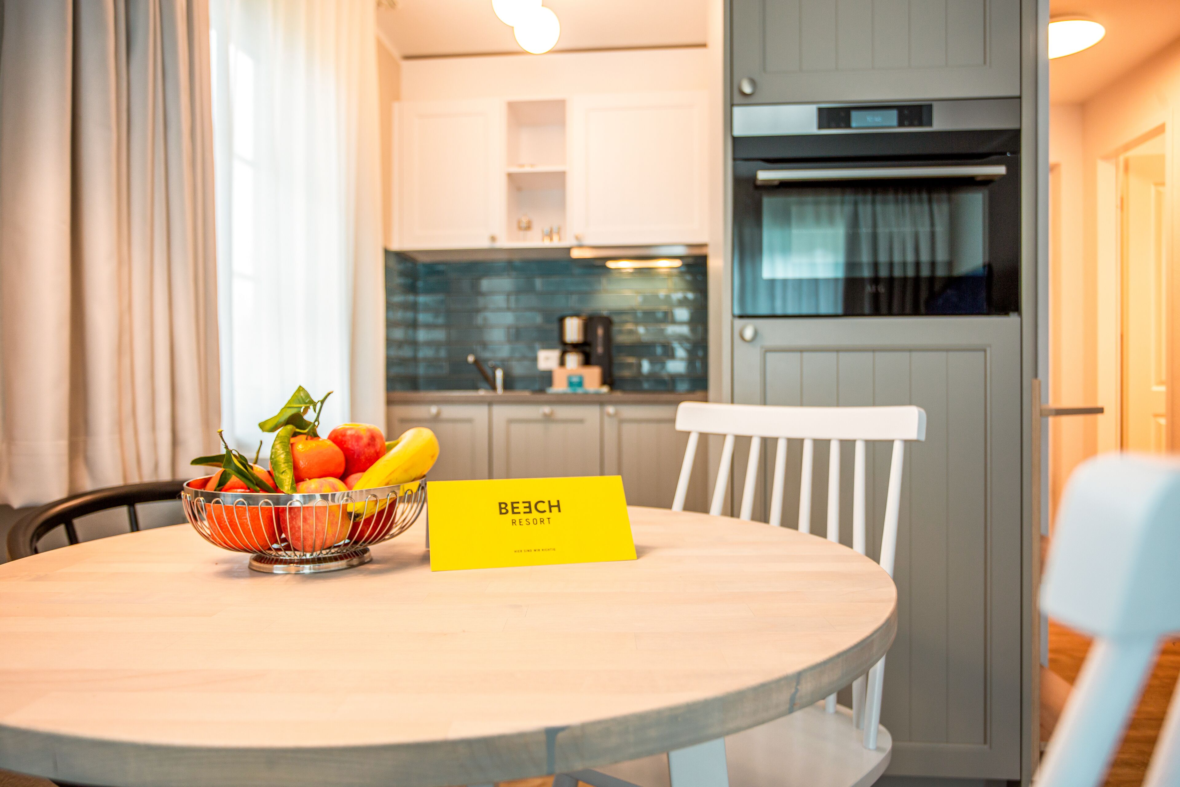 Une table à manger avec un panier de fruits et un panneau jaune portant l’inscription « BEECH RESORT ».