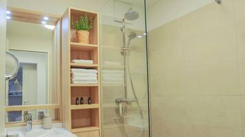 Un baño moderno con cabina de ducha de vidrio, tocador de madera y espejo con marco redondo.