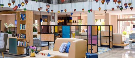 Un moderno vestíbulo de hotel con un sofá, estanterías y luces decorativas colgantes.