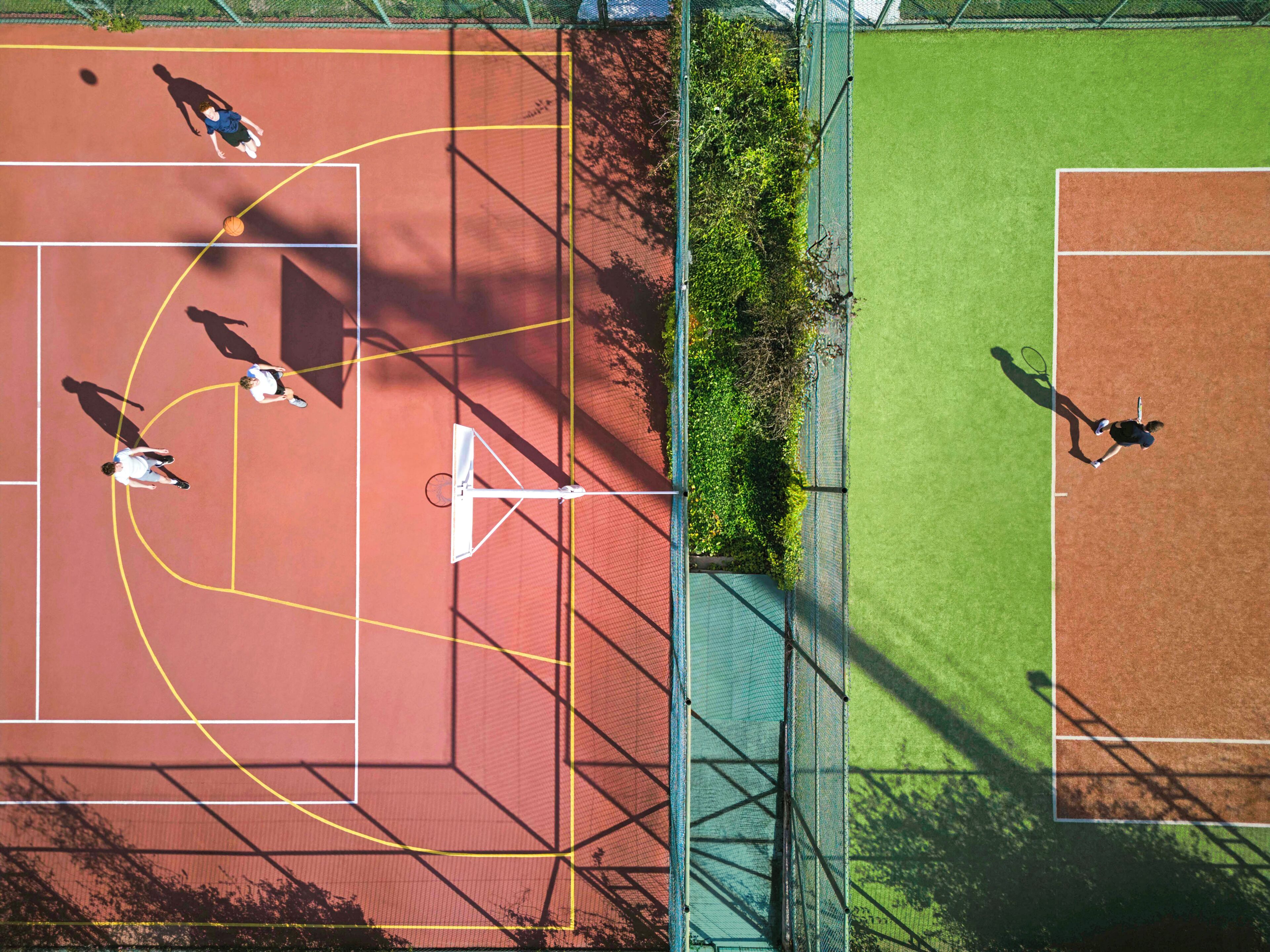 A tennis court with multiple players, a net, and surrounding greenery.